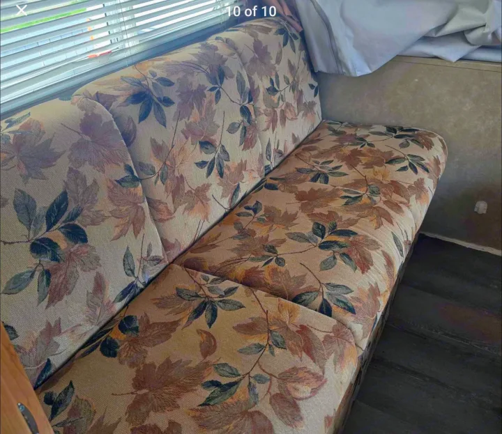 RV rental interior features cozy bench seating with warm autumn leaf upholstery, a window with blinds, and a dark floor.. Starcraft Travel Star 2005
