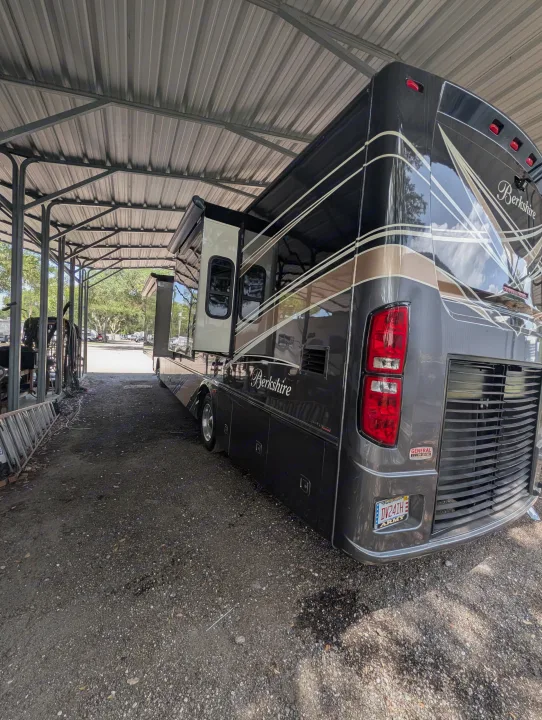 Dark grey Berkshire RV rental with a slide-out, parked under a metal canopy. Perfect for your next road trip adventure.. Forest River Berkshire 2018