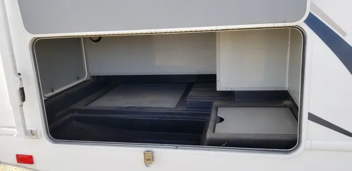 Spacious, empty exterior storage compartment of an rv rental, featuring a molded floor and light grey interior walls, ready for travel gear.. Thor Majestic 2013