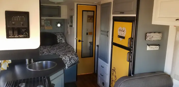 Explore this stylish RV rental interior with a compact kitchen, bed, and vibrant yellow accents on doors & fridge.. Thor Majestic 2013
