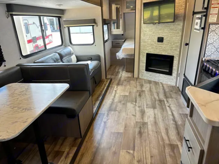 RV rental interior: dinette, kitchen, living area with fireplace & TV, and a partial bedroom view.. Dutchmen Coleman Light 2022
