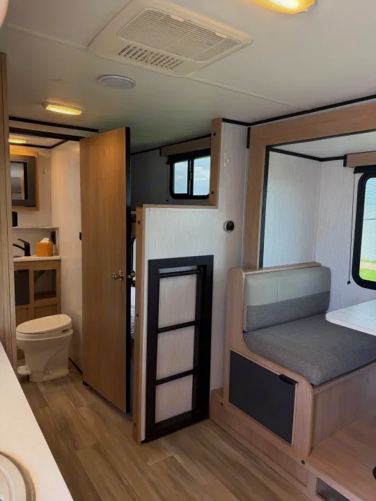 Modern RV rental interior showing a bathroom, dinette area, and bunk bed ladder. Clean and functional travel space.. Cruiser RV Hitch 2022