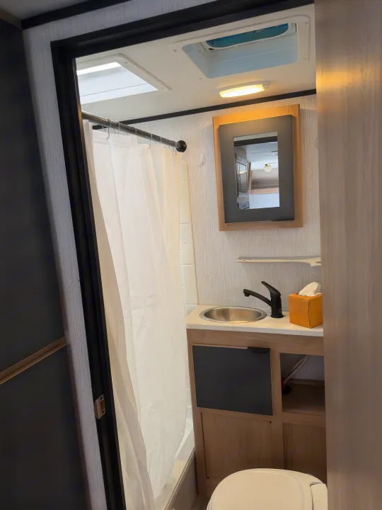 Modern rv rental bathroom featuring a shower, vanity with sink, mirror, and toilet, maximizing space for travelers.. Cruiser RV Hitch 2022