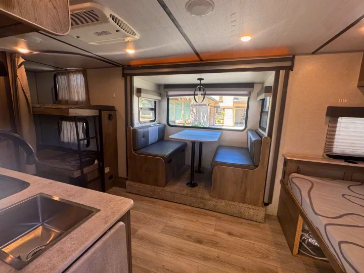 A well-equipped rv rental interior featuring a dinette, bunk beds, and a kitchen sink. Ready for travel!. Forest River Surveyor Legend 2023