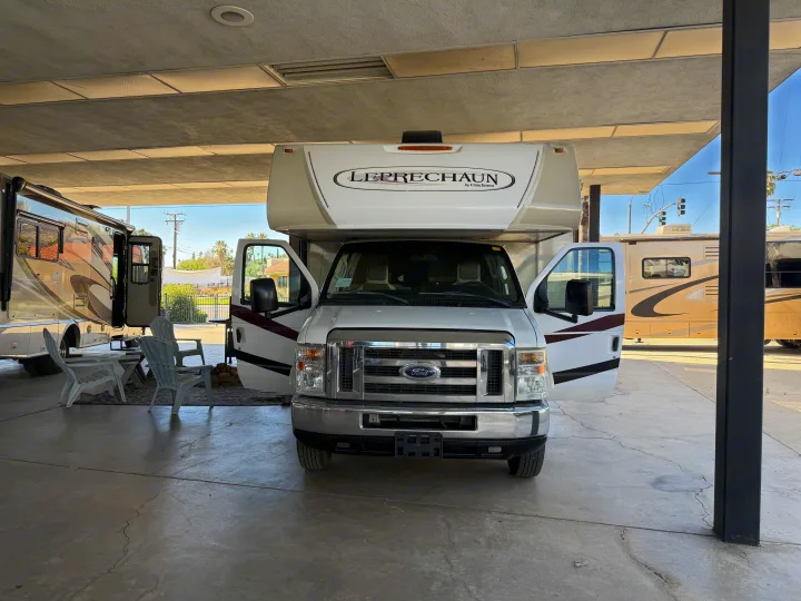 White Leprechaun Class C rv rental with open doors and outdoor seating under a covered structure, ready for adventure.. Coachmen Leprechaun 2018