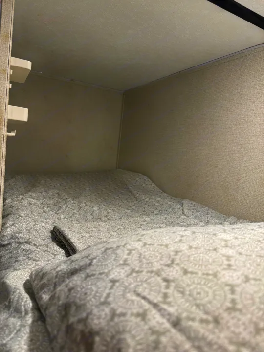 RV rental bunk bed interior with gray patterned bedding, offering a cozy sleeping area in a compact space.. Keystone RV Hideout 2021