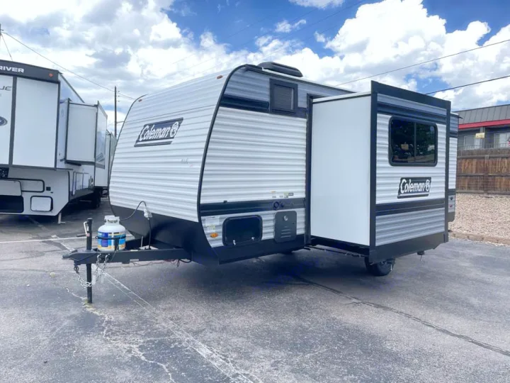 Explore in this Coleman travel trailer, an excellent RV rental option with a convenient slide-out. A propane tank is visible.. Keystone Coleman 19B 2026
