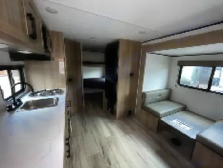 Explore this clean RV rental interior featuring a bright kitchen, dinette, and bunk beds, perfect for your next road trip.. Keystone Coleman 19B 2026
