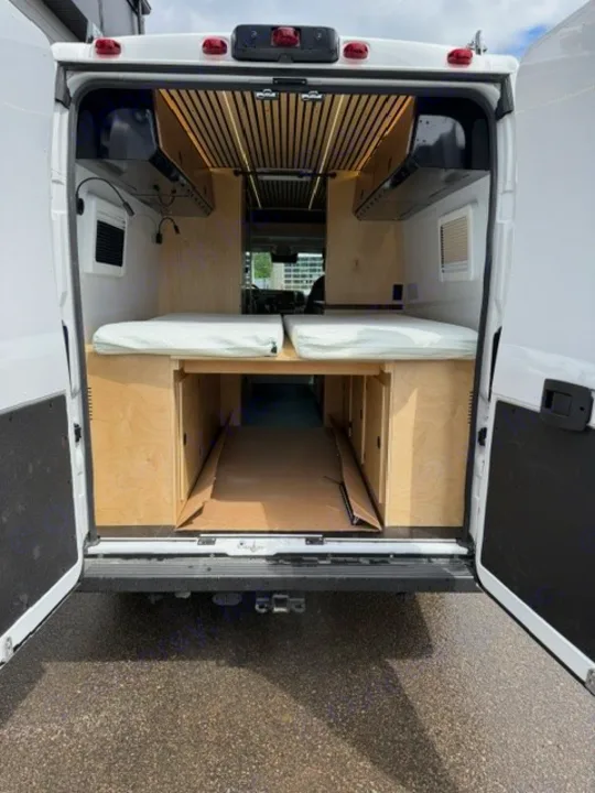 RV rental campervan interior from the rear, featuring two beds with white mattresses & wood storage.. Safari Safari 2025