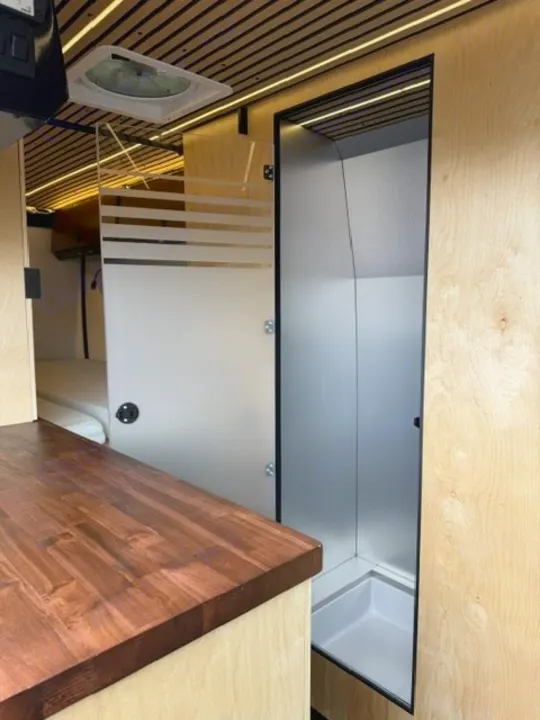 Modern RV rental interior with a bright shower, wooden countertop, and integrated ceiling lights.. Safari Safari 2025