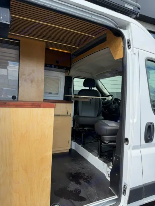Modern RV rental interior with custom wood finishes, slat ceiling, and front cab view. Ideal for travel.. Safari Safari 2025