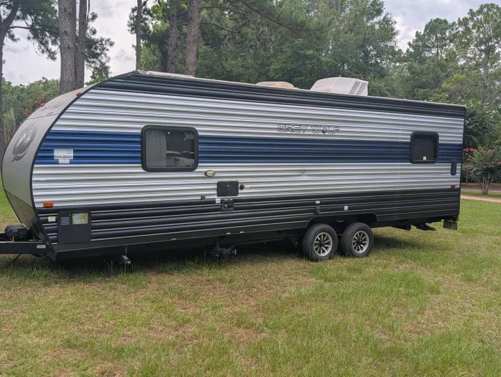 An rv rental, a Grey Wolf travel trailer, silver with blue accents, parked on grass for outdoor adventures.. Forest River Cherokee Grey Wolf 2021