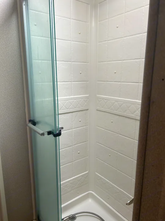 Bright, clean, compact shower stall with a glass door and white textured walls inside an RV rental. Perfect for travel comfort.. Entegra Coach Odyssey 2019