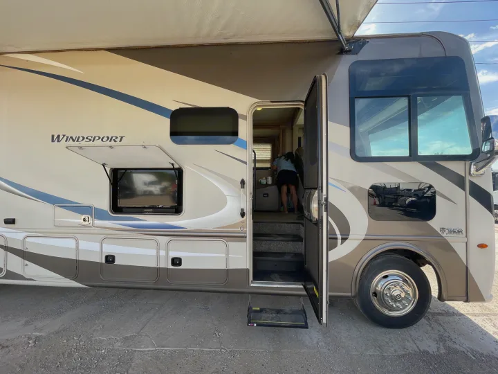 Detailed view of an RV rental: a Thor Windsport motorhome with an open door, awning, and outdoor TV for convenience.. Thor Windsport 2019