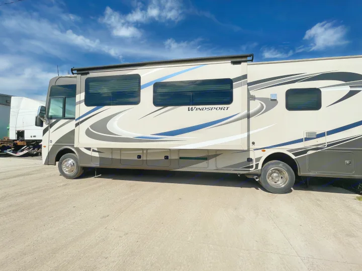 This large Class A motorhome, perfect for an rv rental, is parked outdoors on a bright day with its slide-out extended, under a blue sky.. Thor Windsport 2019