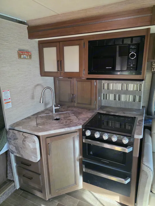 Well-equipped rv rental kitchen featuring a Greystone microwave, Furrion stove/oven, sink, and ample cabinets.. Thor Chateau 2021