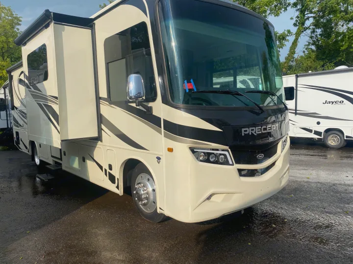 A cream and black Jayco Precept Class A motorhome, ideal for rv rental, with extended slide-outs on wet pavement.. Jayco Precept 2022