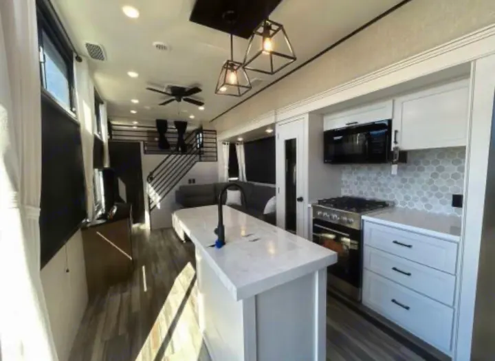 Modern rv rental interior featuring a bright kitchen island, stove, and spacious living area with stairs.. Jayco Jay Flight Bungalow 2025