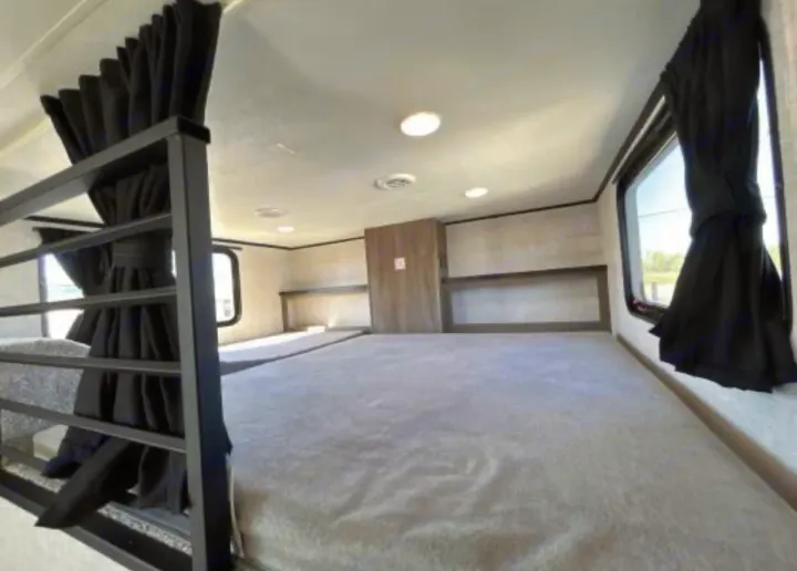 Cozy rv rental bunk beds: featuring black curtains, shelves, and bright lighting, offering a comfortable sleeping space for travelers.. Jayco Jay Flight Bungalow 2025
