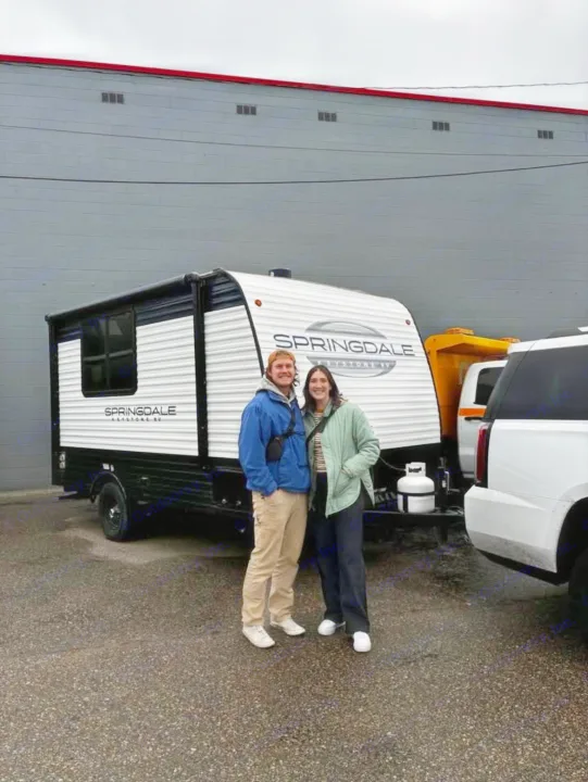 A joyful couple stands in front of their new Springdale travel trailer. Explore more with an RV rental adventure!. Keystone RV Springdale Mini 2025
