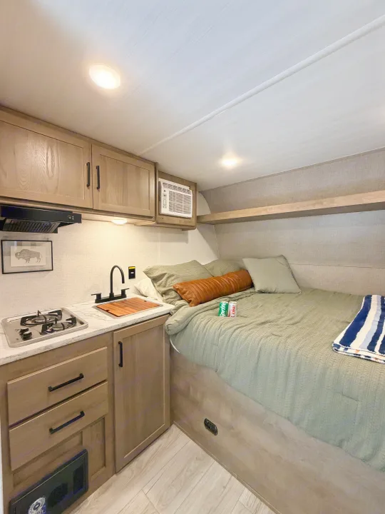Modern rv rental interior featuring a compact kitchen, comfortable bed, and an AC unit for cozy travel.. Keystone RV Springdale Mini 2025