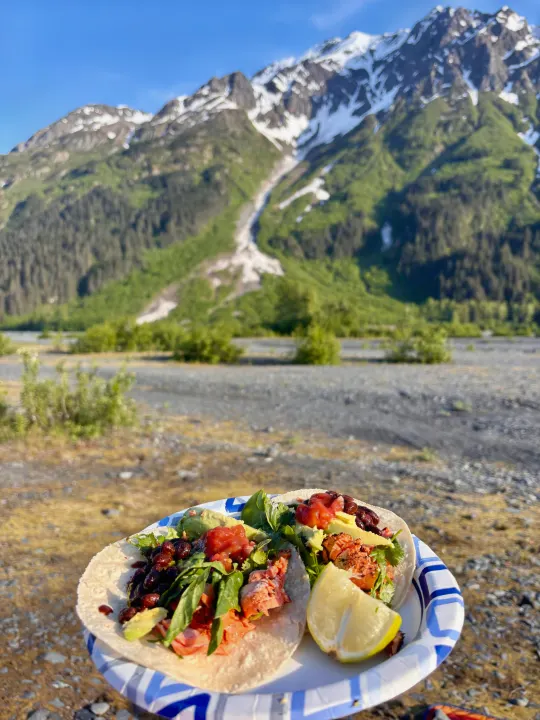 Fresh salmon tacos, avocado & salsa on a paper plate, set against a stunning snowy mountain landscape. Perfect RV rental view!. Keystone RV Cougar 2018
