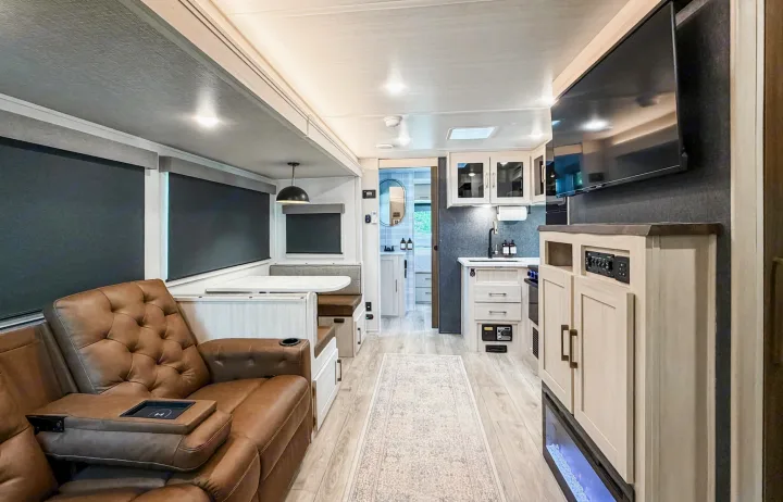 Modern and spacious RV rental interior with light wood, grey walls. Features comfortable recliners, kitchen, dining, & a TV fireplace.. Forest River Surveyor Legend 2026