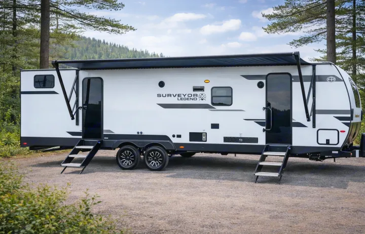 Explore the outdoors with this sleek white Surveyor Legend RV rental, perfectly set up with an awning and steps for camping adventures.. Forest River Surveyor Legend 2026