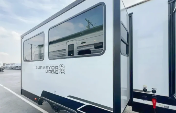 Modern white Surveyor Legend RV rental, showcasing its side with large windows and a slide-out section.. Forest River Surveyor Legend 2026