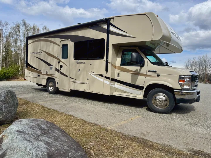 Tan Coachmen Leprechaun Class C **rv rental** parked on gravel near trees, under a cloudy sky.. Coachmen Leprechaun 260DS Ford 450 2019