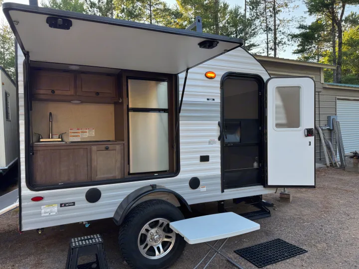 Explore this rv rental: a travel trailer showcasing its open outdoor kitchen with a sink, fridge, and cabinets.. Sunset Park RV SunRay 2022