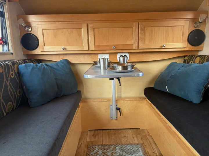 Cozy RV rental interior featuring a compact dining area with wooden cabinetry, cushioned benches, and a small table.. nuCamp T@B CS-S 2017