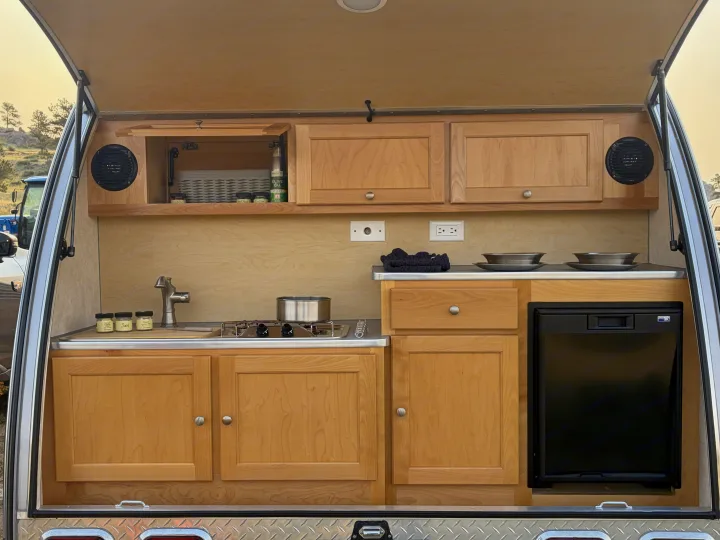 RV rental: Compact camper galley kitchen with sink, stove, fridge, speakers, and wooden cabinets, ready for your trips.. nuCamp T@B CS-S 2017