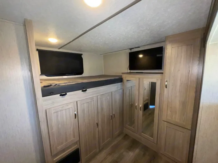 RV rental: bunk bed with window, below-bed storage cabinets, TV, and a mirrored wardrobe. Functional and organized.. Coachmen Freedom Express 320BHDSLE 2021