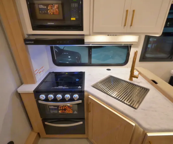 This RV rental features a compact, modern kitchen: microwave, gas stove, oven, and stylish sink. Ideal for travel cooking.. Thor Chateau 2026