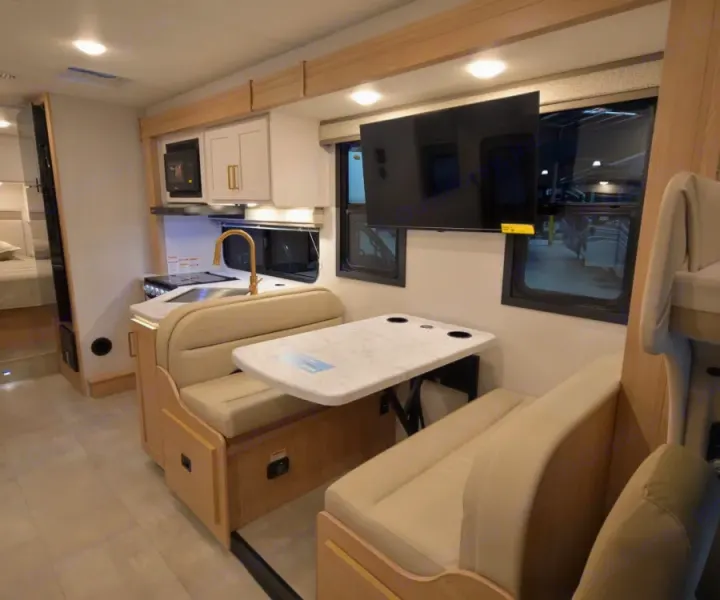 Well-appointed RV rental interior with a compact kitchen, dinette, TV, and sleeping area. Perfect for travel and mobile living.. Thor Chateau 2026