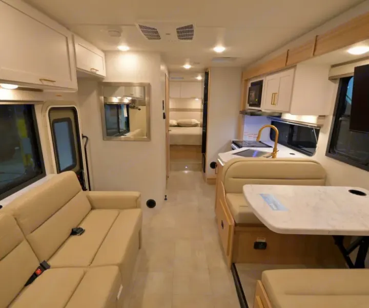 Bright and modern RV rental interior featuring a cozy living area, compact kitchen, dining nook, and rear bedroom.. Thor Chateau 2026