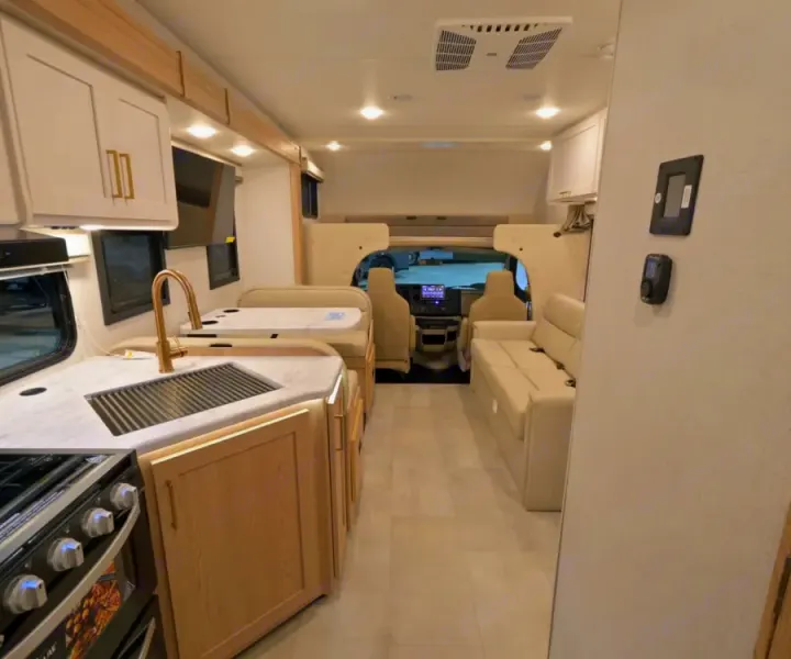 Bright rv rental interior featuring a modern kitchen with sink, dinette, and comfortable sofa seating. Ready for adventures.. Thor Chateau 2026