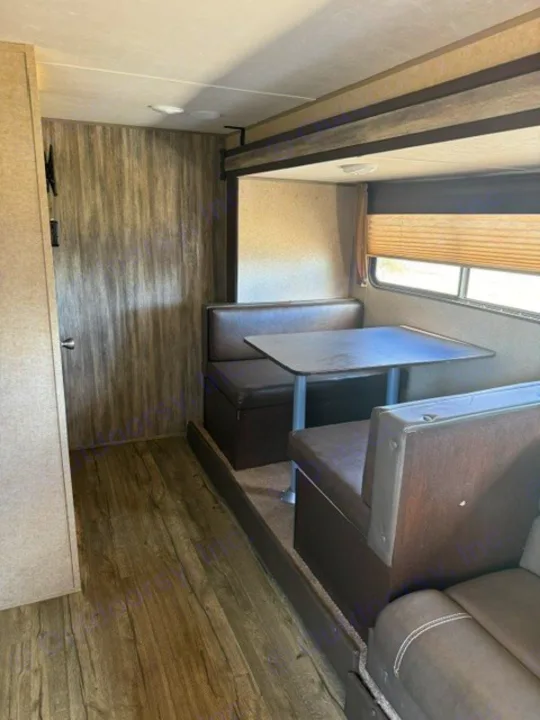 RV rental interior featuring a dinette with booth seating, a table, and wood-look flooring, with a window and blinds.. Forest River Cherokee Wolf Pup 2018