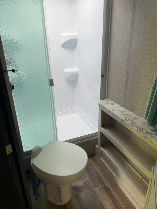 RV rental bathroom: white shower, toilet, wood-look floor, and marble-style vanity with shelves. Ready for your adventure.. Jayco Jay Flight 2021