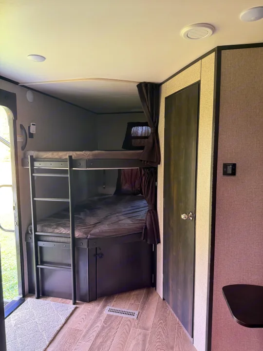 RV rental interior features bunk beds with a ladder, privacy curtains, and a wall-mounted control panel.. Jayco Jay Flight 2021