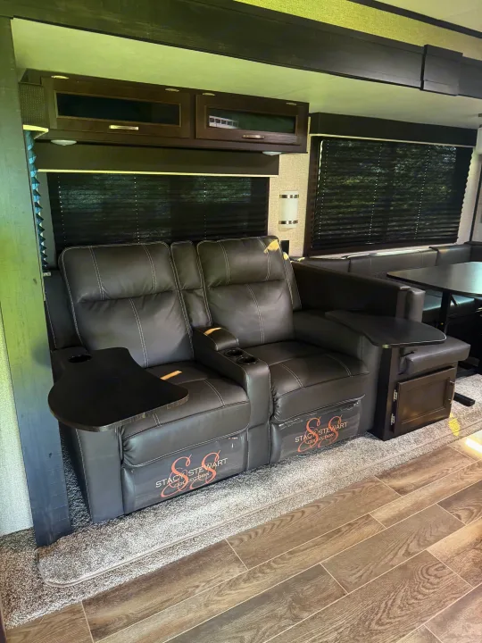 Cozy grey reclining theater seats with side tables and cup holders in a modern RV rental. Features a rear dinette and dual flooring.. Jayco Jay Flight 2021