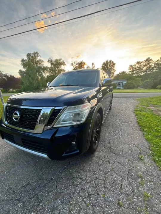 A dark blue SUV is parked on a cracked driveway at sunset. Consider an RV rental for spacious travel adventures.. Nissan 2017 Nissan Armada Platinum 4WD V8 2017