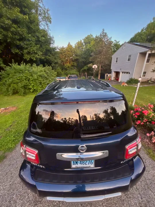Dark blue SUV on gravel driveway, backyard trees & house visible. Ready for any travel adventure, even an rv rental trip!. Nissan 2017 Nissan Armada Platinum 4WD V8 2017