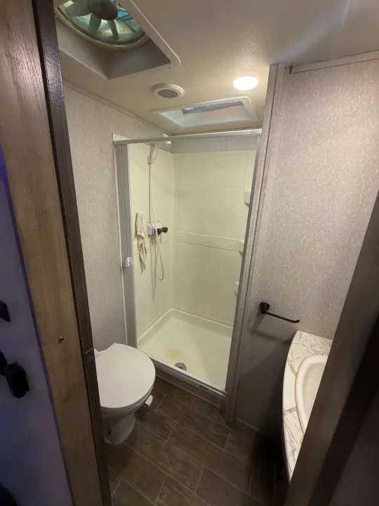 This RV rental bathroom features a compact shower, toilet, and sink, designed efficiently for travel.. Forest River Artic wolf 2022