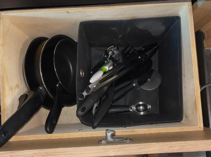 Organized RV rental kitchen drawer featuring nested pans and essential cooking utensils in a practical fabric bin. Space-saving.. Forest River Coachmen Freelander 2015