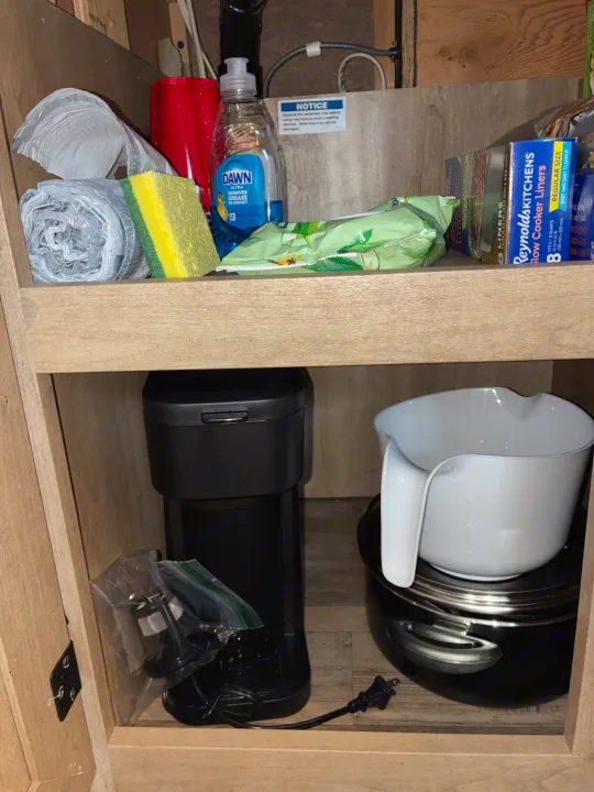 RV rental kitchen cabinet packed with cleaning and cooking essentials: Dawn soap, sponge, slow cooker liners, coffee maker, slow cooker.. Forest River Coachmen Freelander 2015
