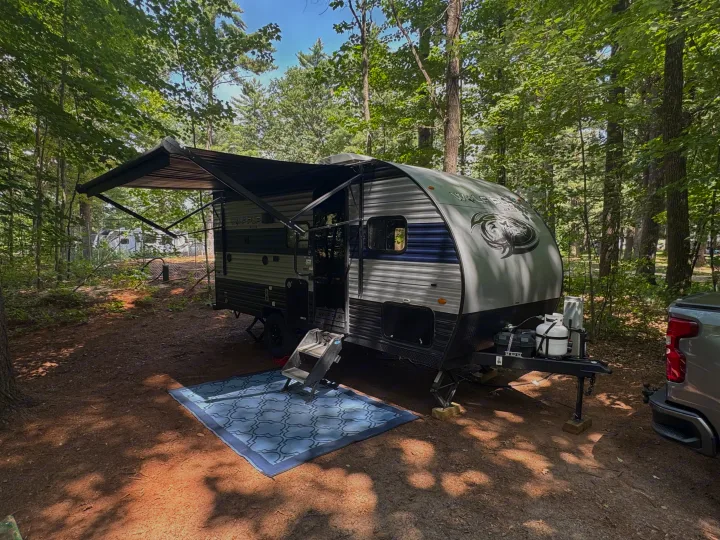 This Wolf Pup RV rental is perfectly set up at a serene wooded campsite, ready for a relaxing outdoor adventure.. Forest River Cherokee Wolf Pup 2022