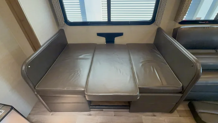 An RV rental dinette with comfortable cushions, ready to convert from dining to sleeping, featuring a window and table bracket.. Jayco Precept 2019