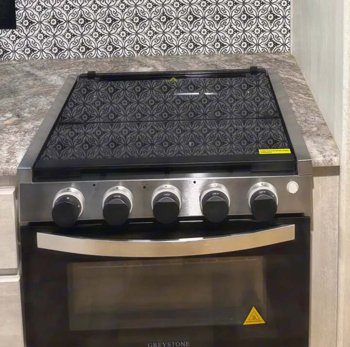 RV rental kitchen features a sleek Greystone stove, oven, and a decorative tile backsplash.. Forest River Shasta 2022